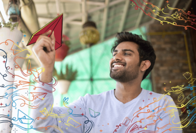 A man who has been practicing origami holding up a paper plane